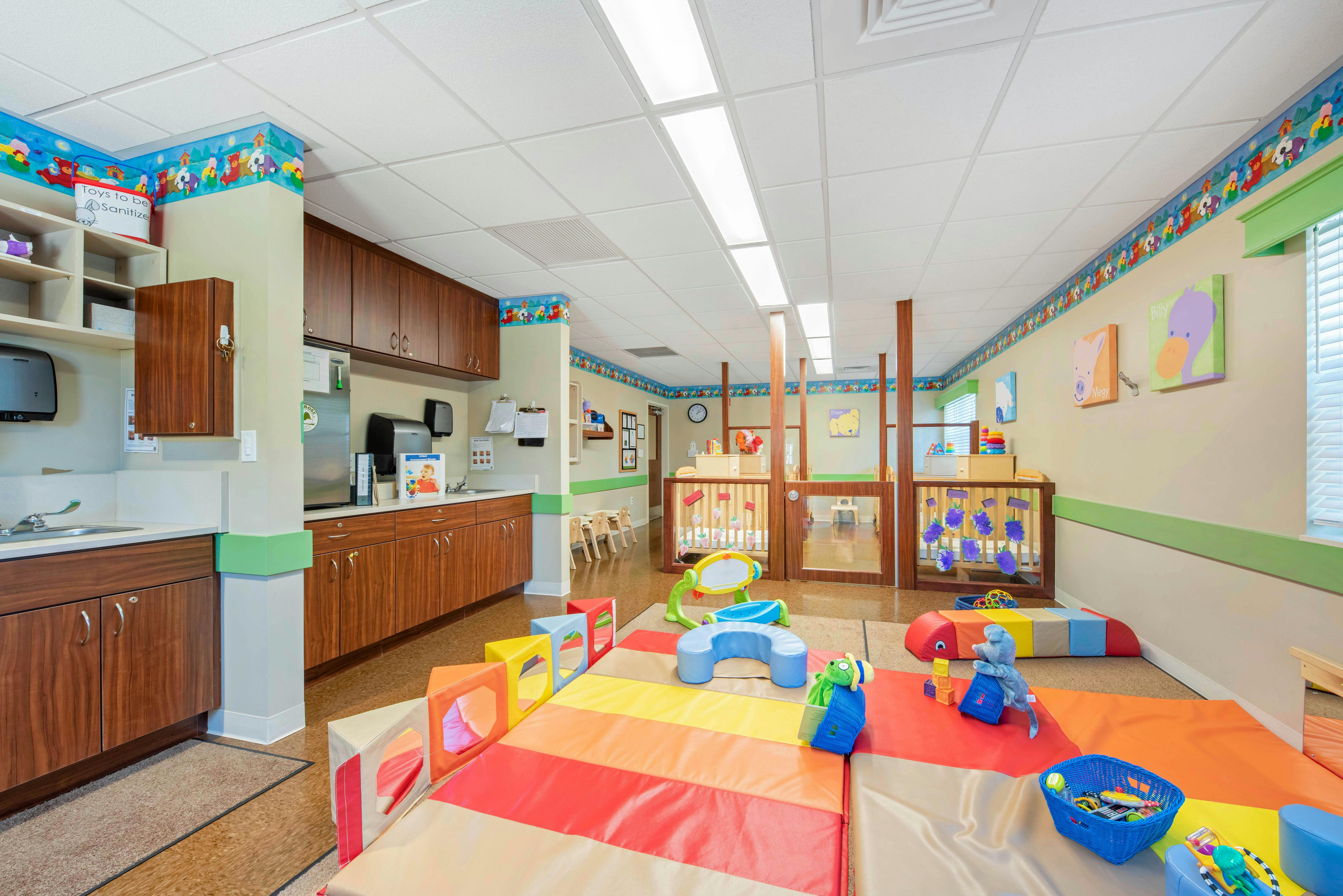 Colorful playroom with soft mats, cribs, and child-sized furniture