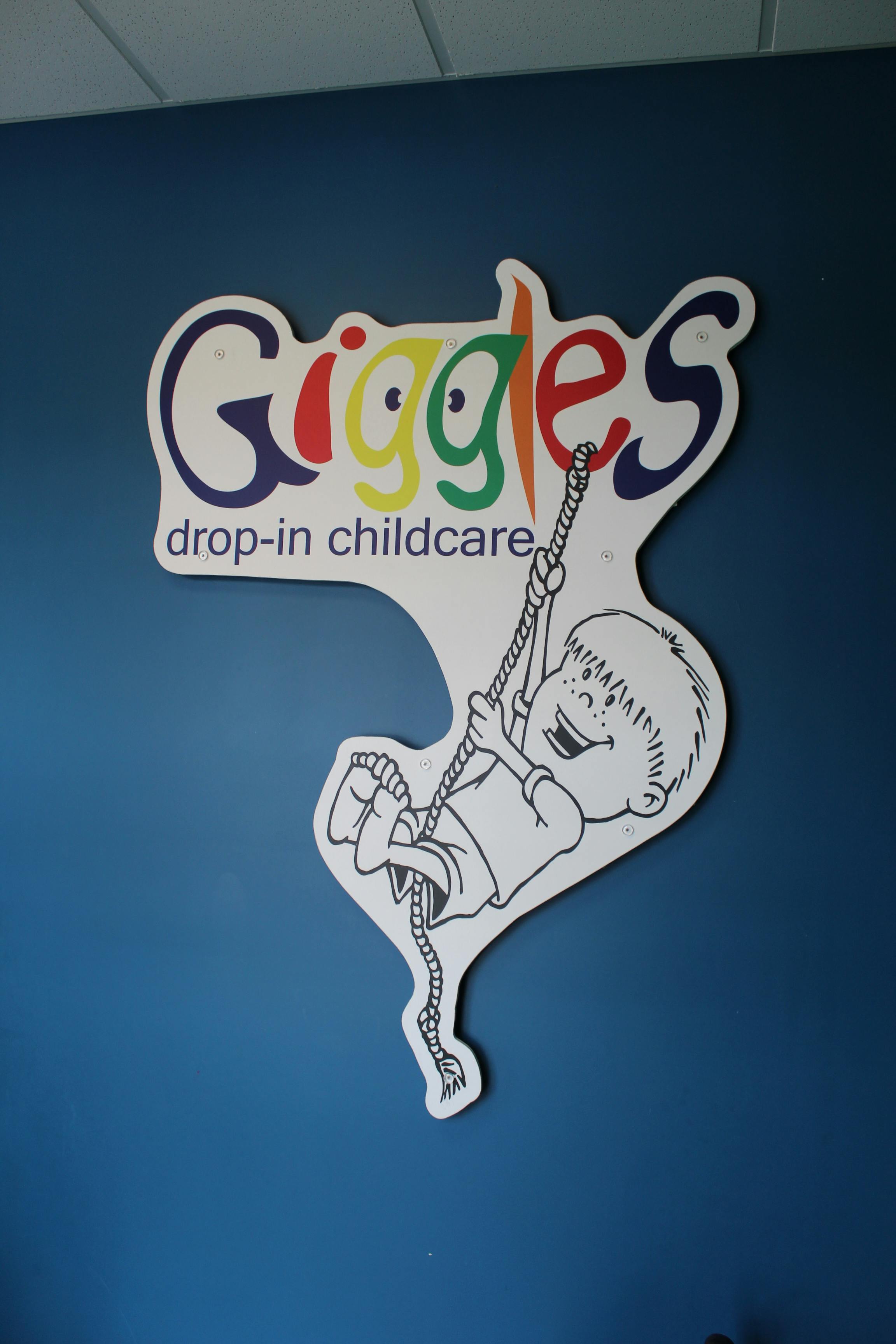 Giggles drop-in childcare sign with a child swinging on a rope