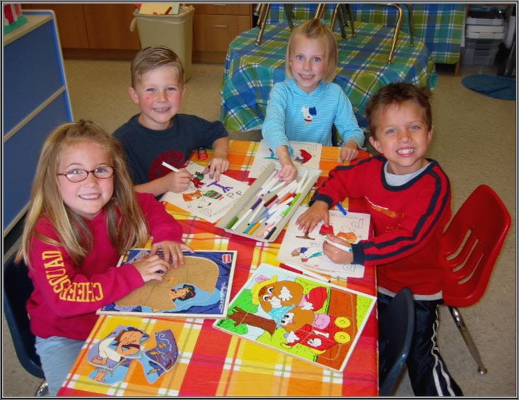 Four children sitting at a table with puzzles and coloring pages to-do lists