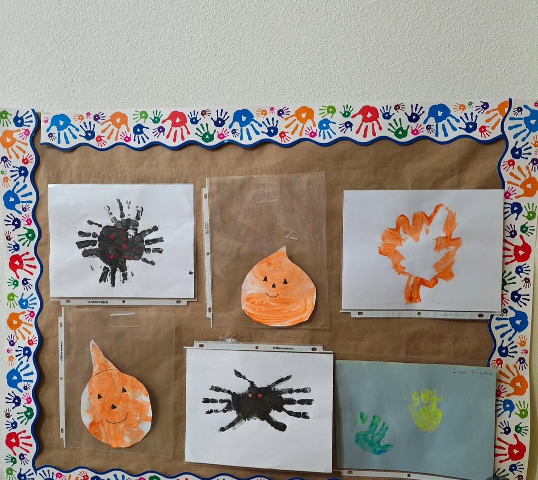Bulletin board displaying seasonal child artwork of spiders and pumpkins