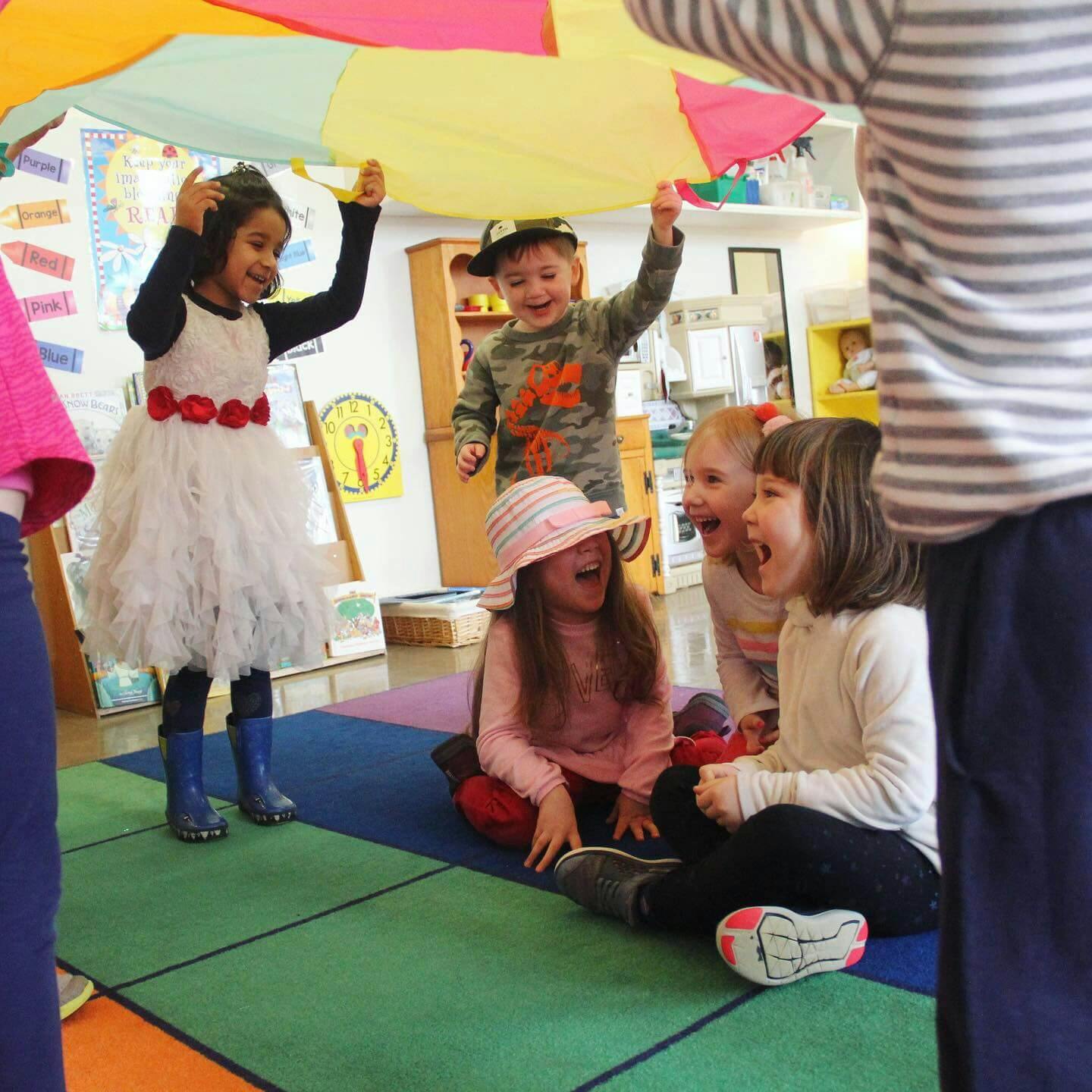 Children playing with a colorful parachute indoors