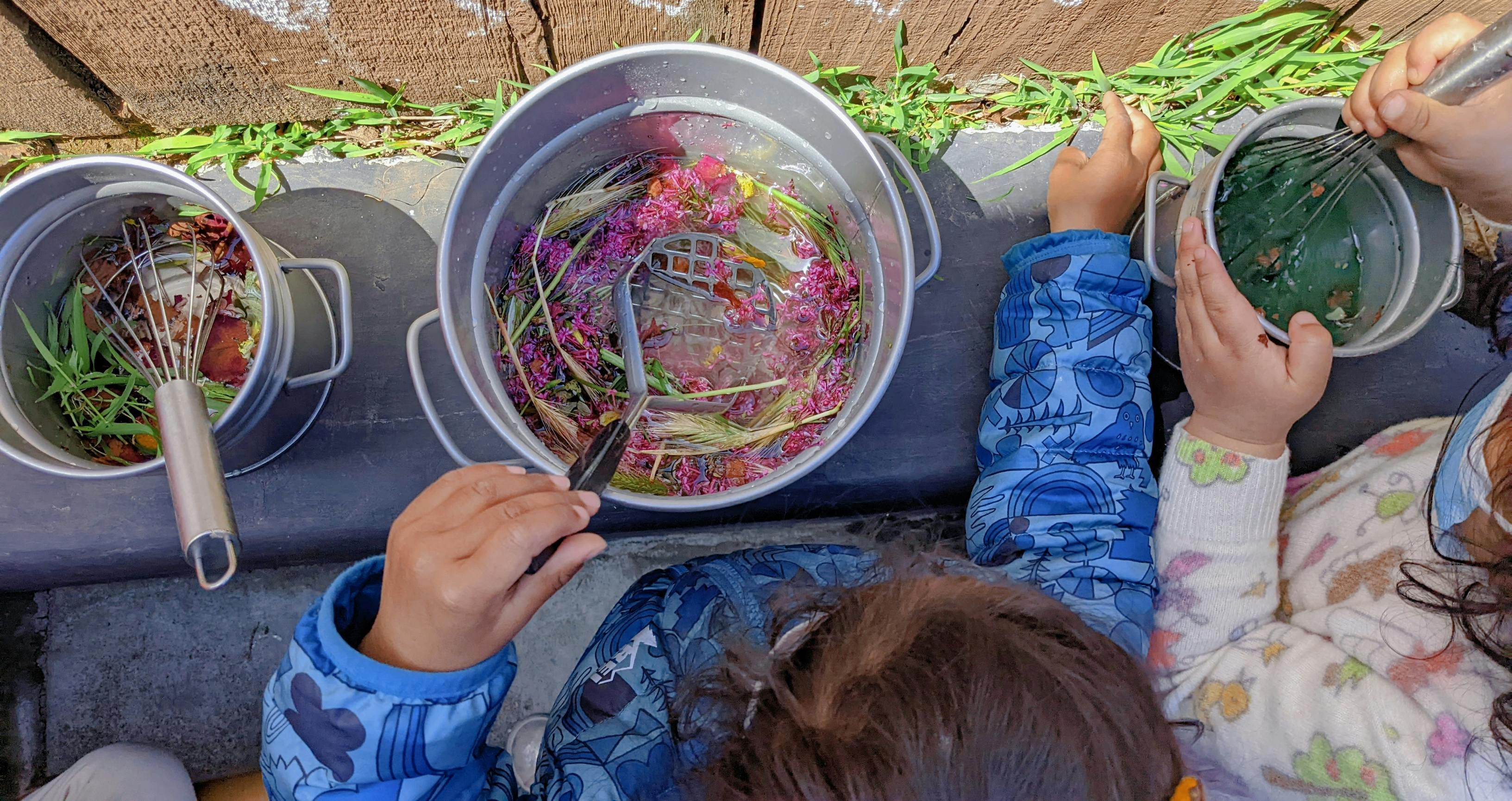 Children playing with buckets of flowers and leaves