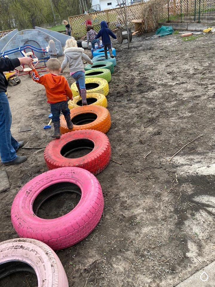 Children stepping through colorful tires on the ground