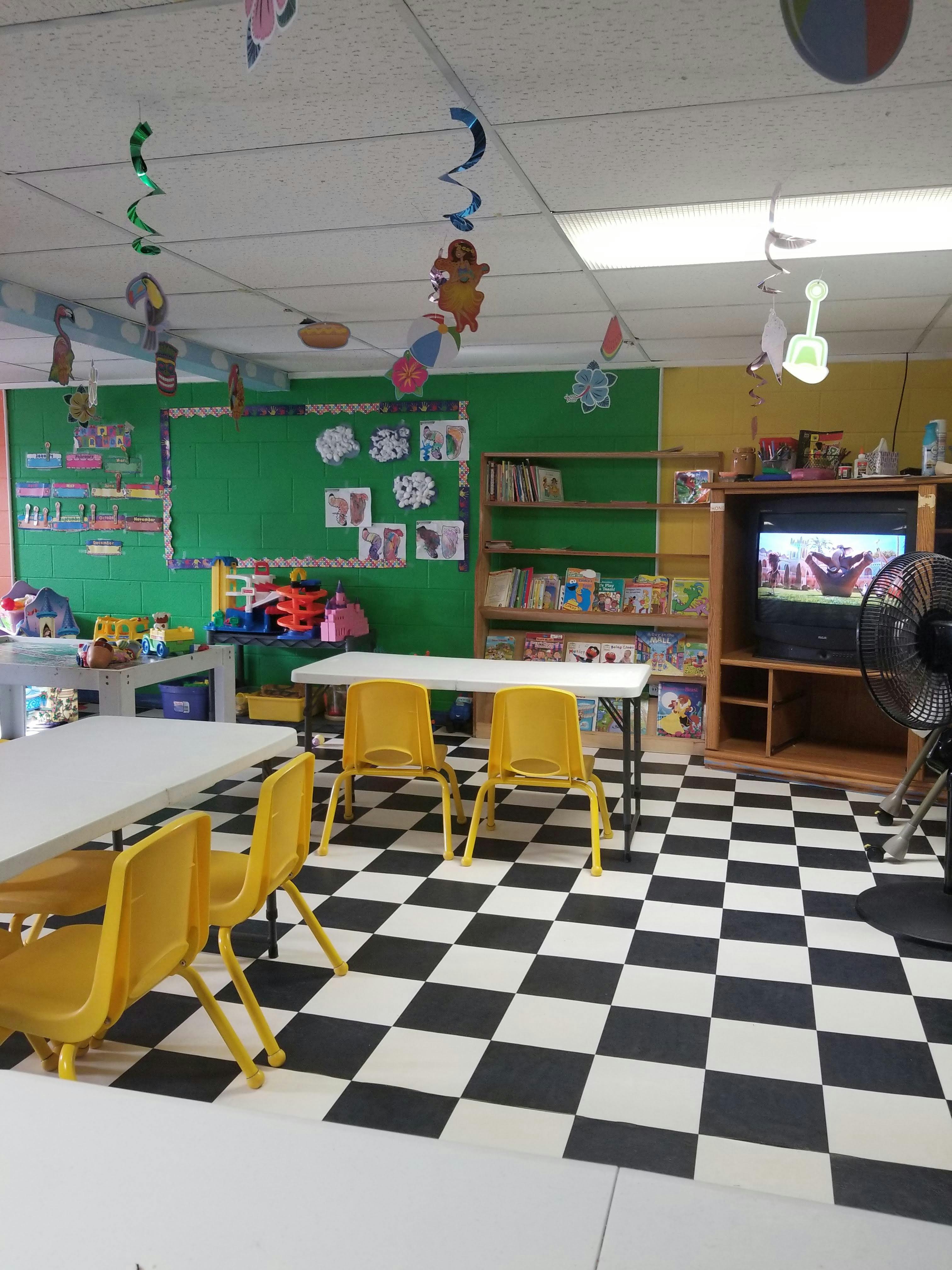 Classroom with small tables and yellow chairs, green and yellow walls, checkered floor