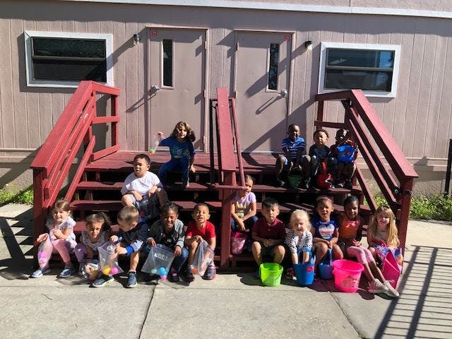 Group of children and adults sitting on and in front of red stairs