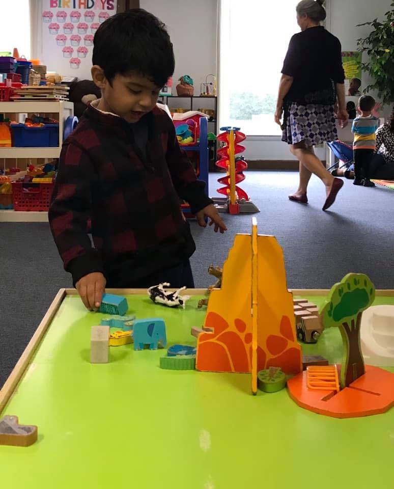 Child playing with toys on a green table in a classroom