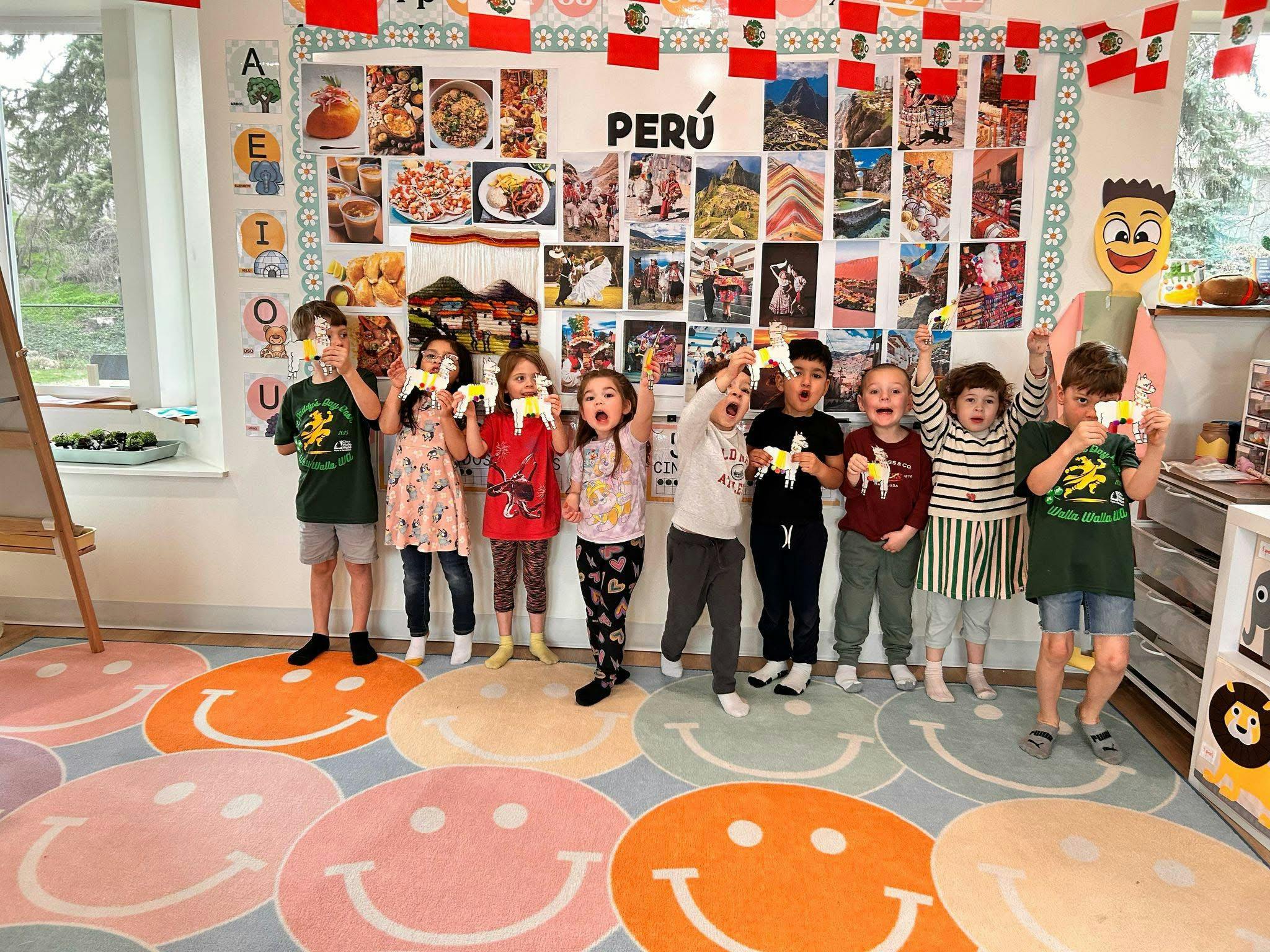 Children holding up paper stars in a classroom with a Peru display