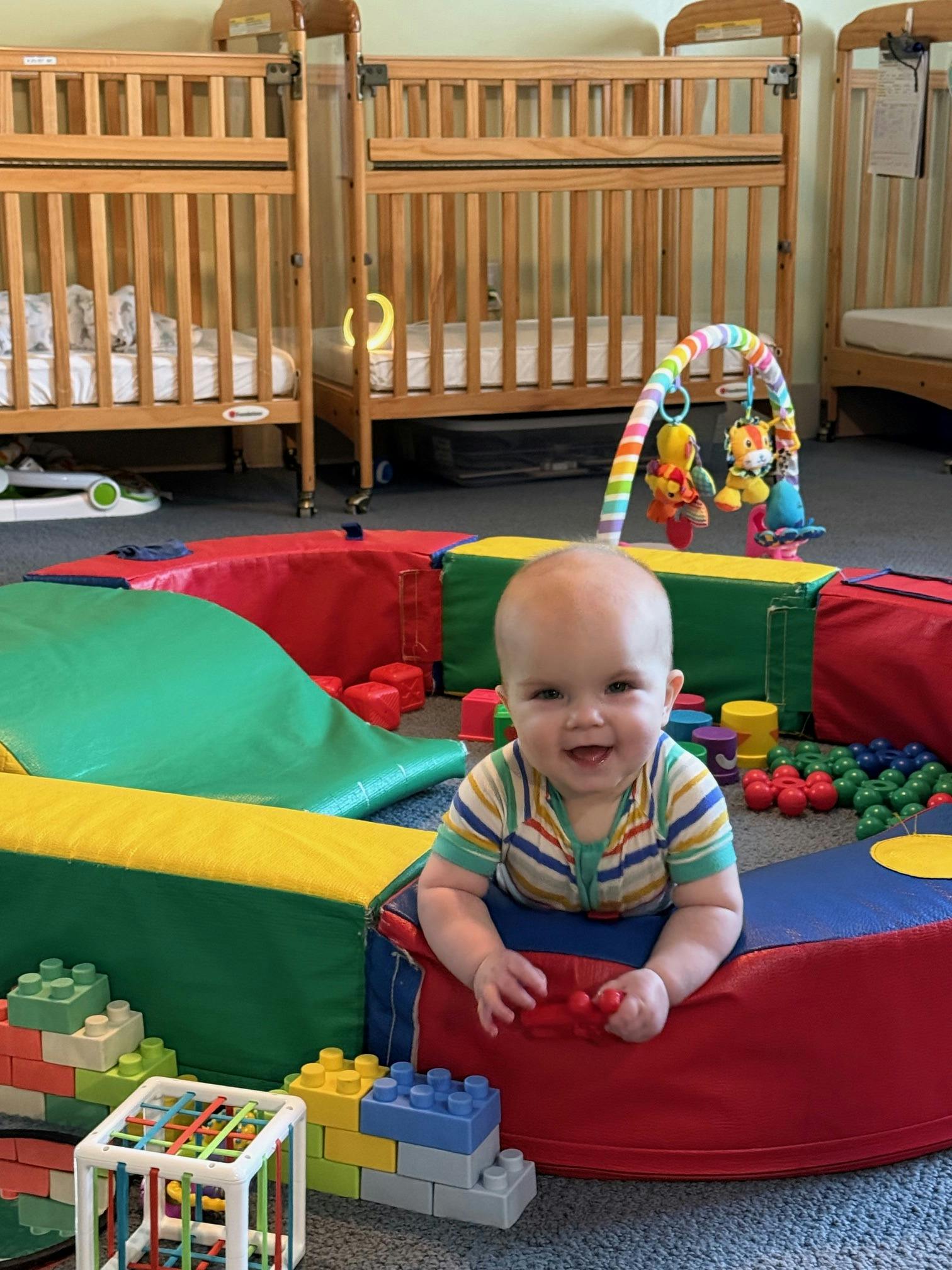 Child in a colorful play area with soft blocks and toys