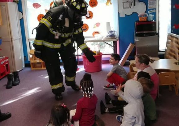 Firefighter in full gear interacting with children in a classroom