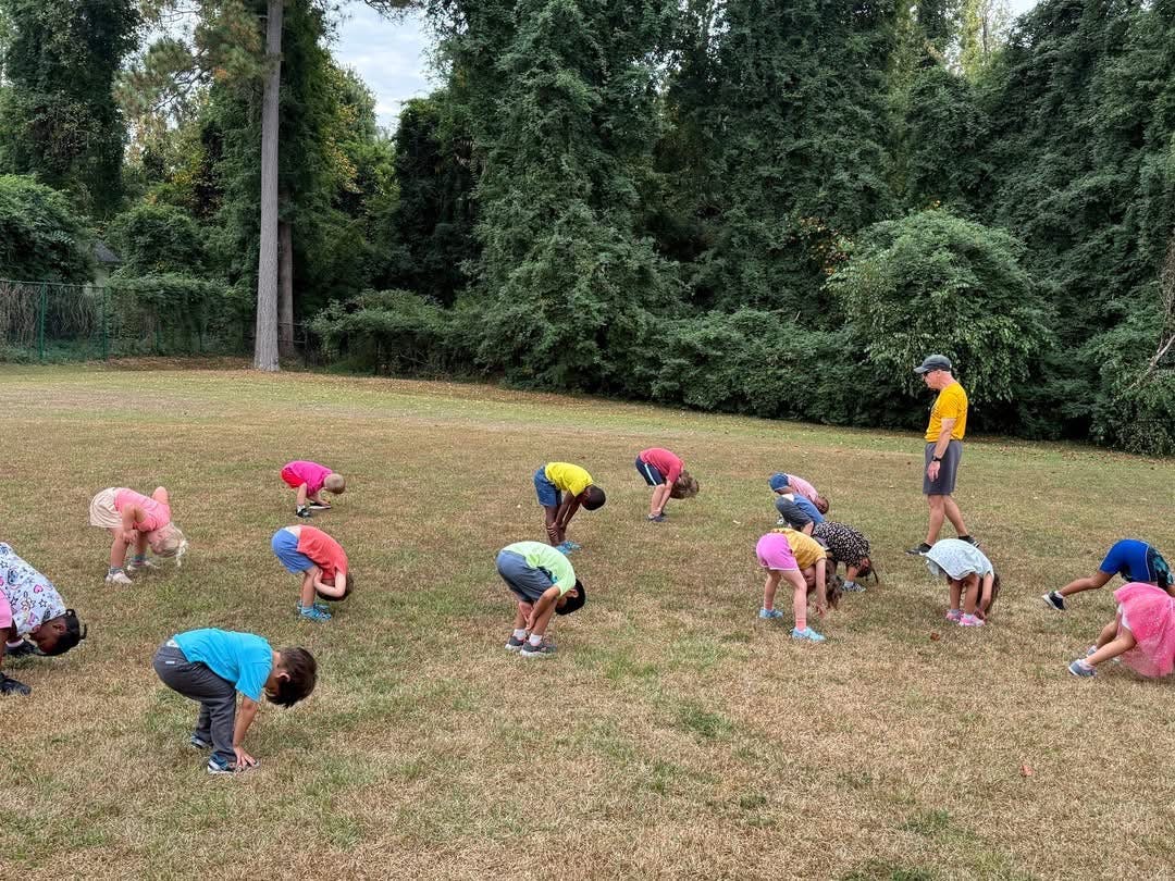 Adult and children bending over in a grassy field