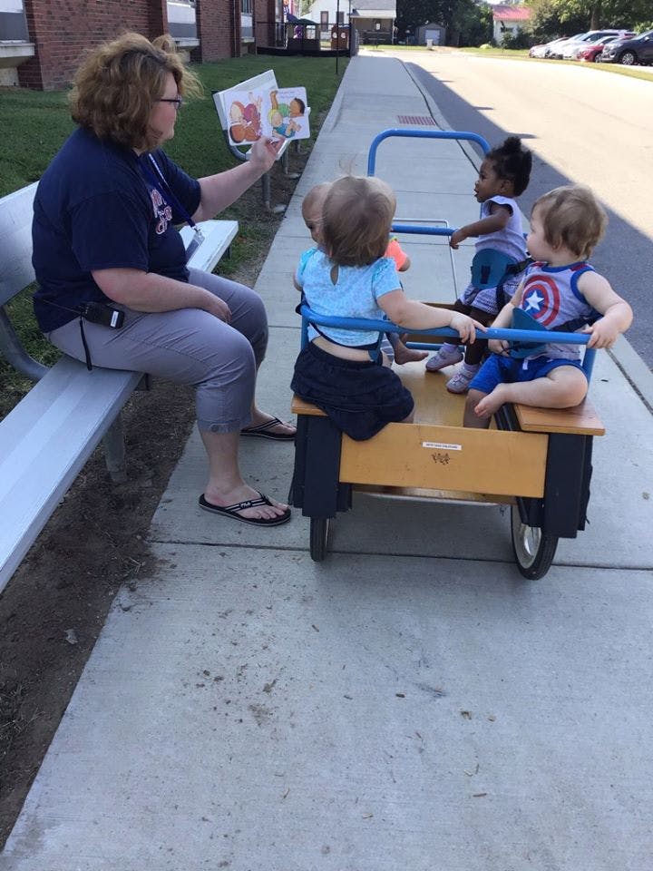 Person reading a book to three children in a wagon