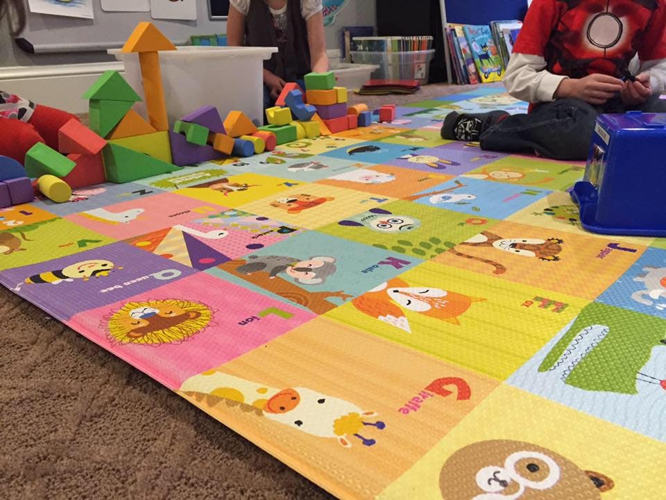 Child playing with blocks on a colorful alphabet mat