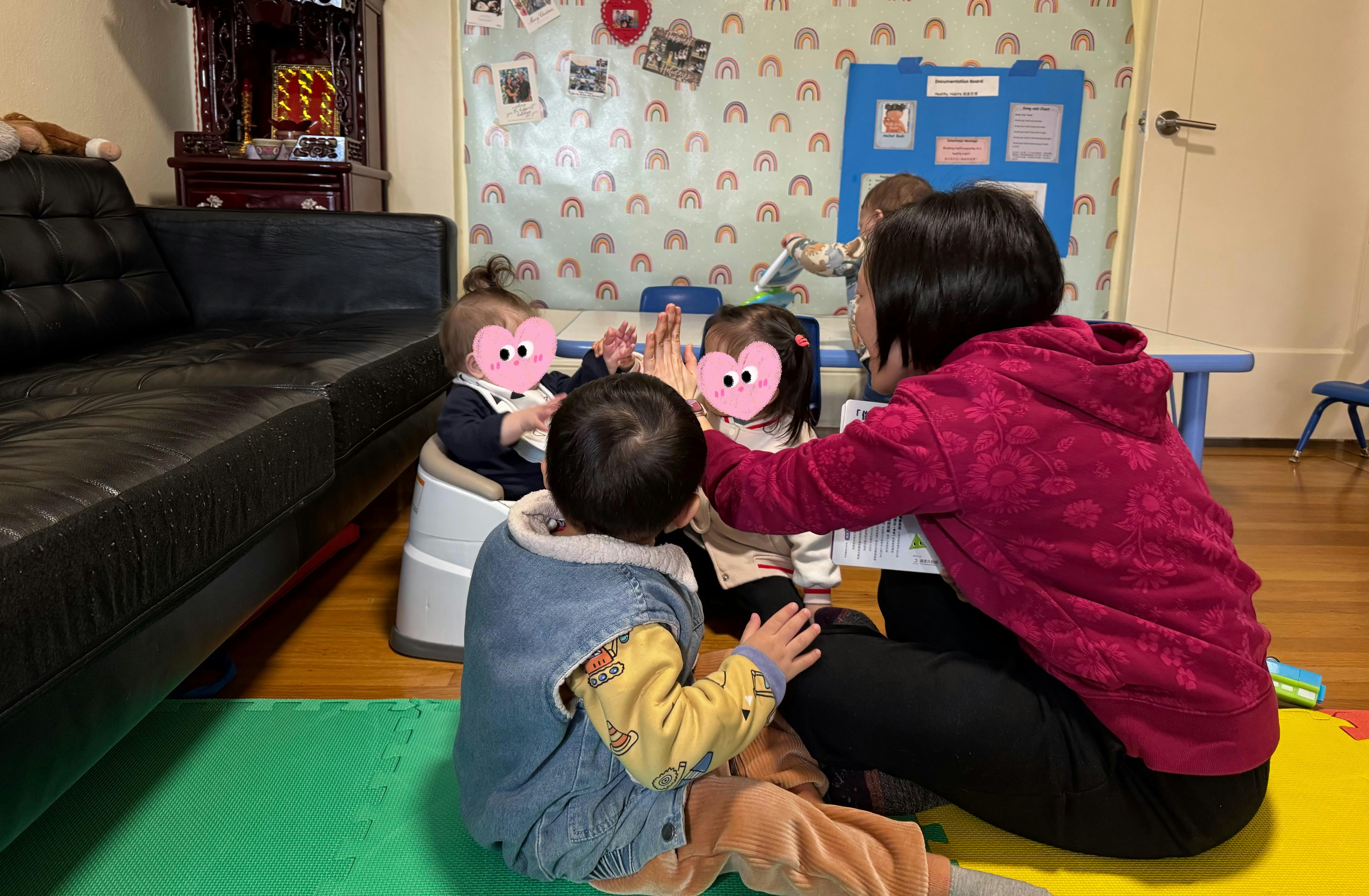 Adult and three children interacting on the floor in a play area