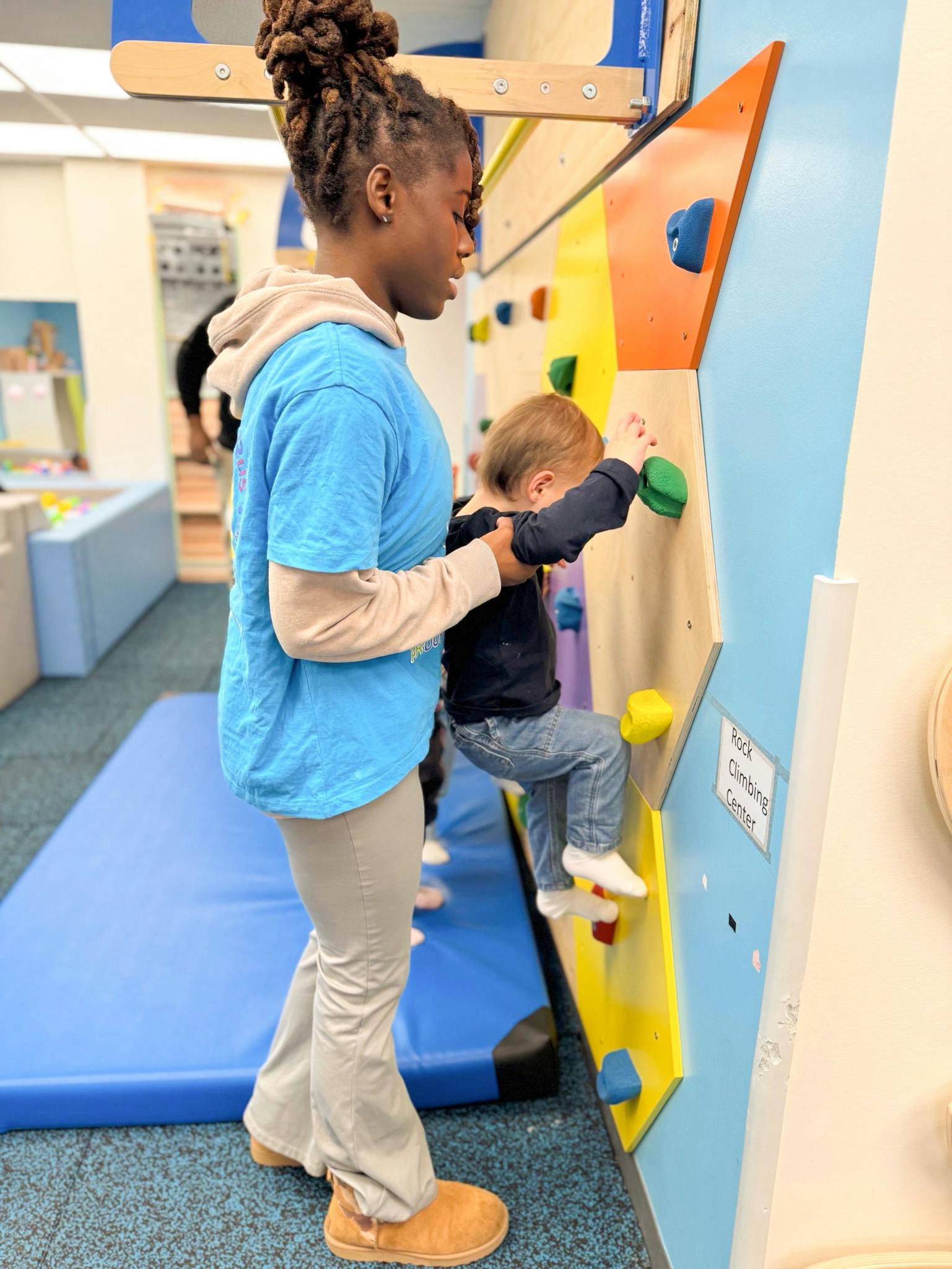 Person assisting a child on a climbing wall