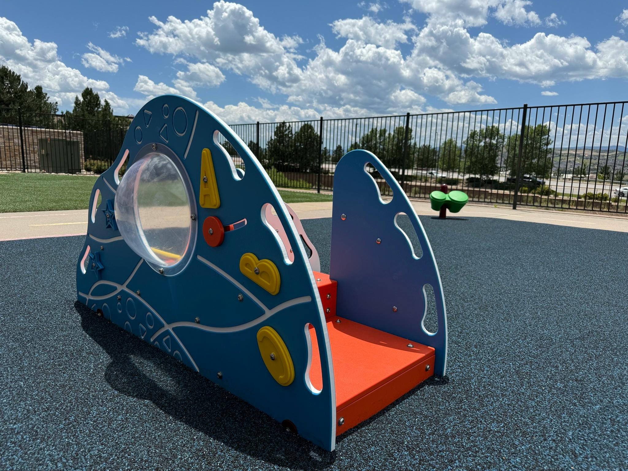 A blue and orange play structure on a dark blue playground surface