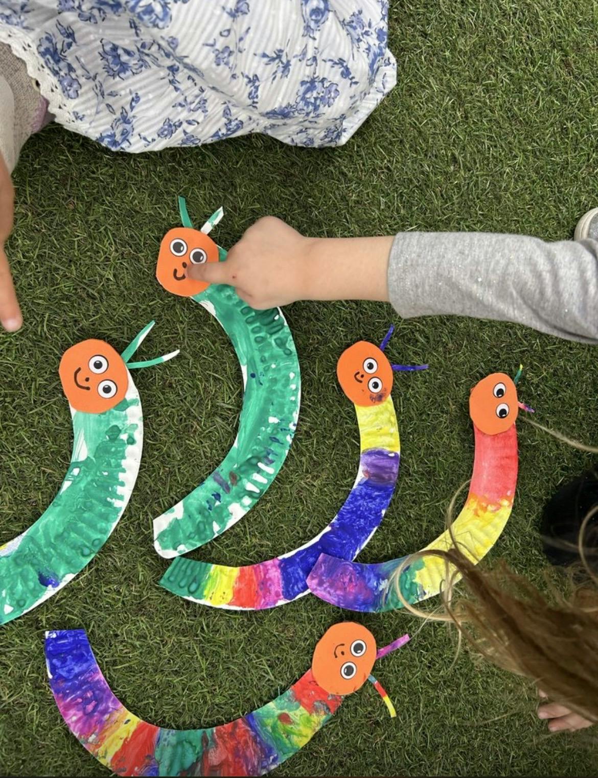 Child touching paper caterpillar craft on grass
