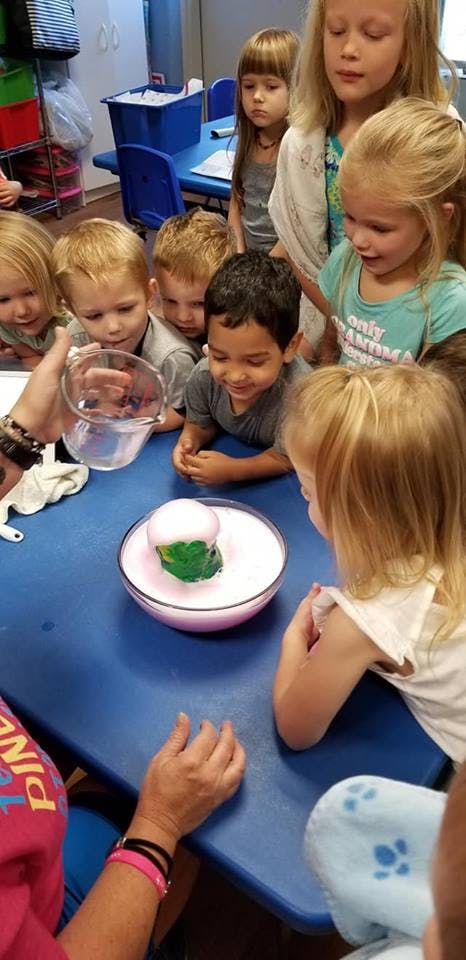 Children watching a science experiment with a bubbling bowl