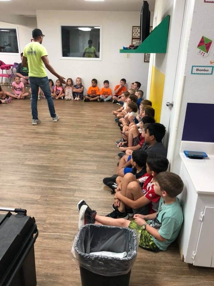 Person standing in front of children sitting on the floor