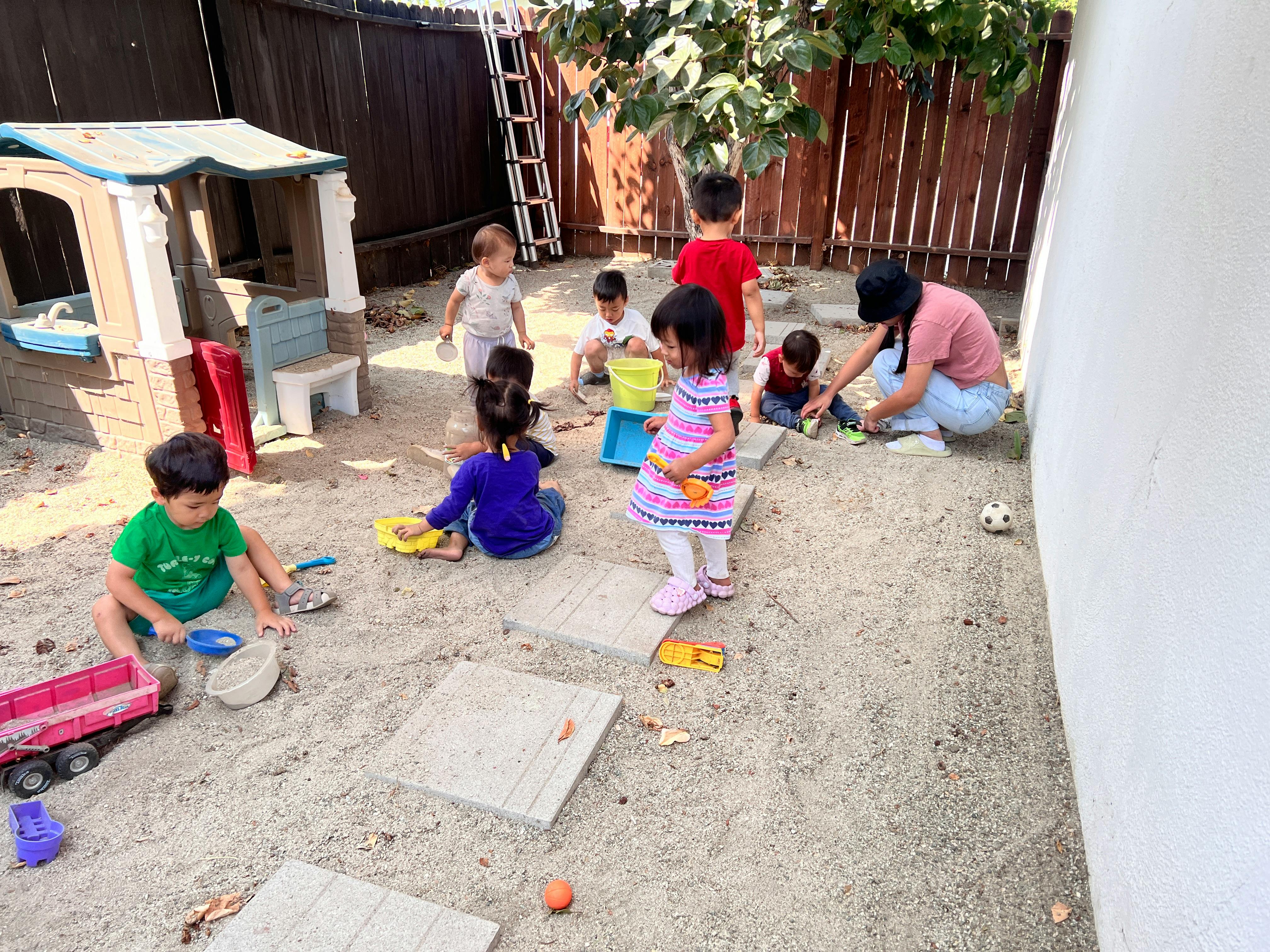 Children and an adult playing in a sandbox