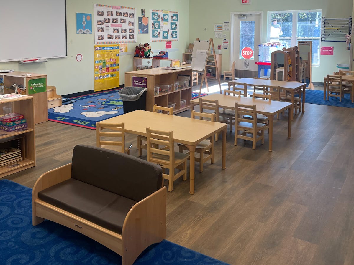 Empty classroom with small wooden tables and chairs, and a small sofa