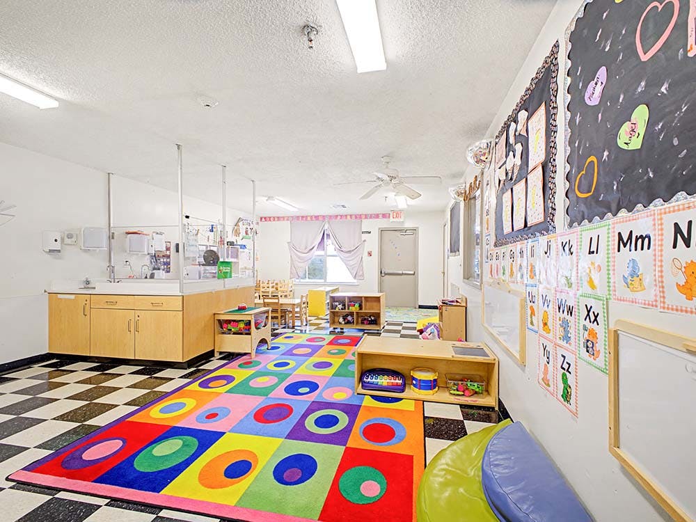 Colorful classroom with a play rug and alphabet charts on the wall