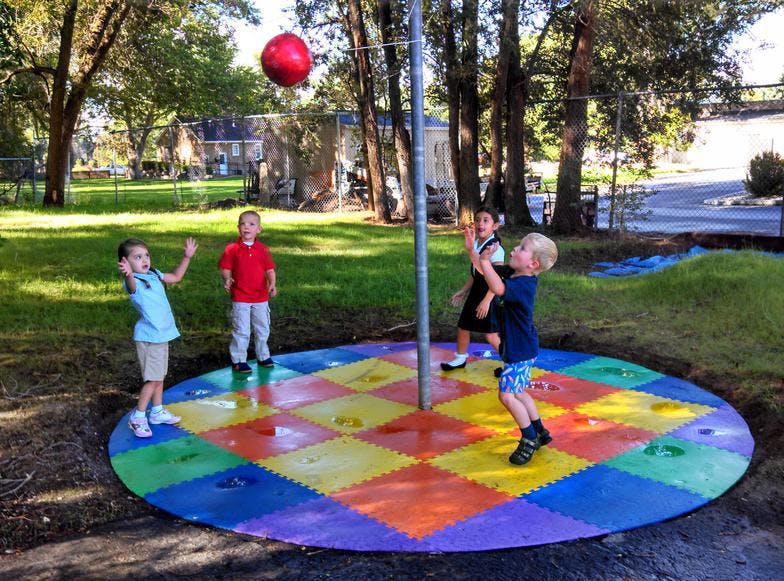 Children playing tetherball on a colorful mat