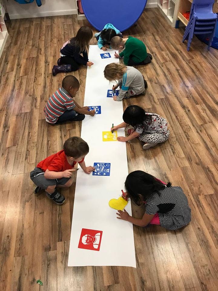 Children on the floor coloring on a long sheet of paper