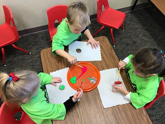Three children painting at a table