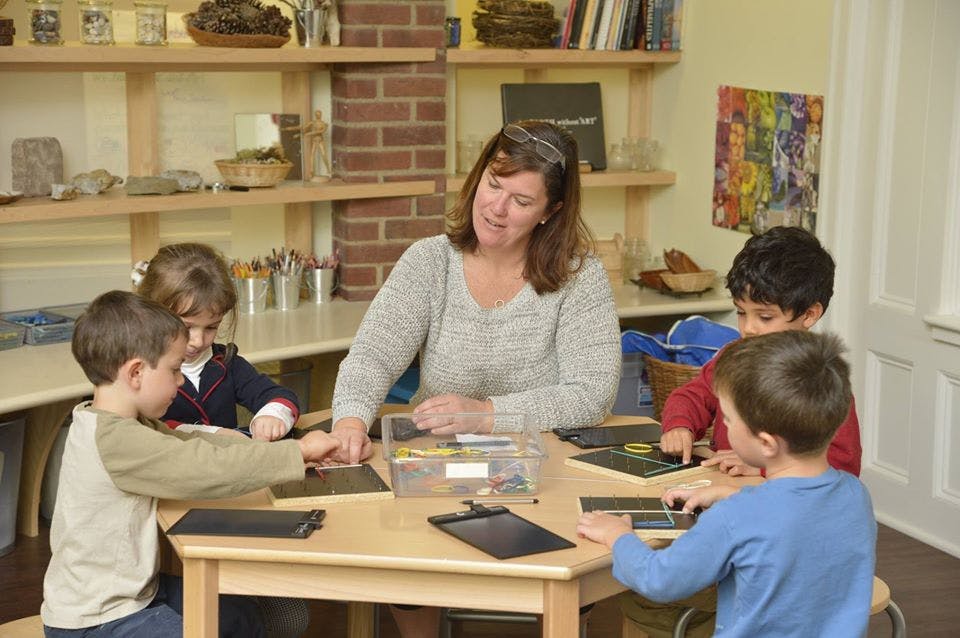 Adult and children at a table working with small black tablets