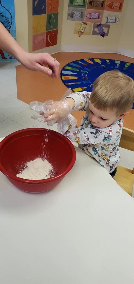 Child pouring flour into a red bowl
