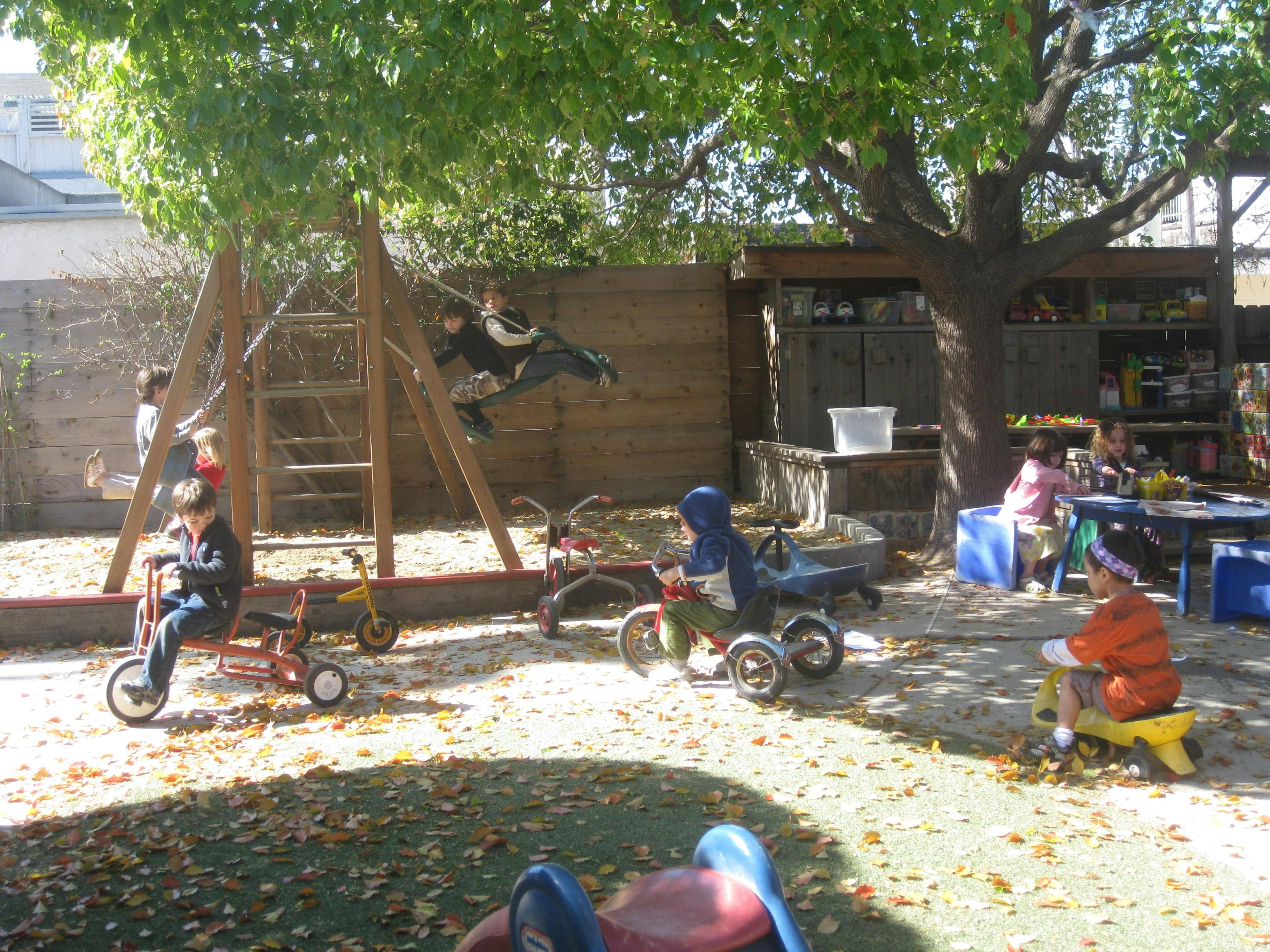 Children playing on tricycles and climbing structure in a playground