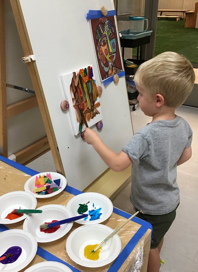 Child painting on an easel in a classroom