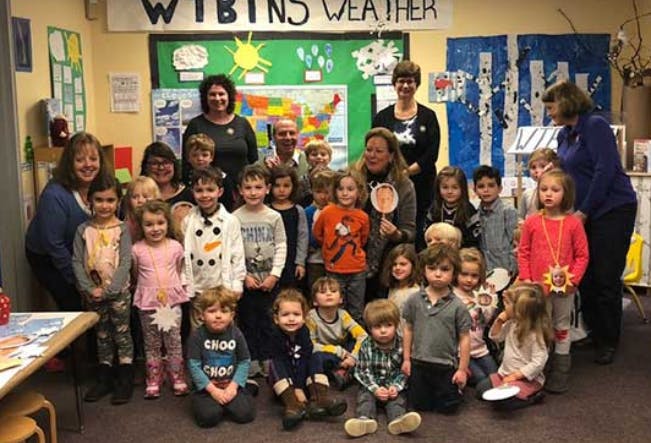 Group of adults and children posing in a classroom