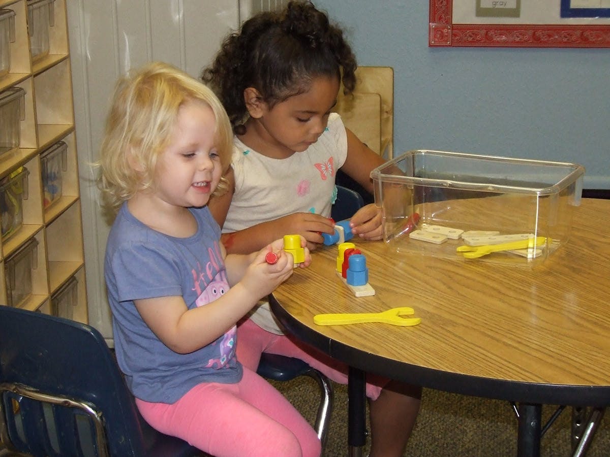 Two children playing with colorful blocks at a table