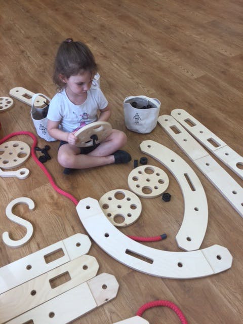 Child sitting on floor playing with wooden construction toy pieces