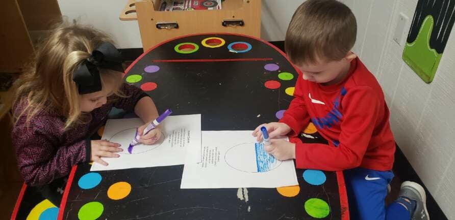 Two children drawing at a table