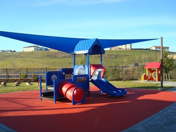 Playground with blue shade structure, red tunnel, and blue slide