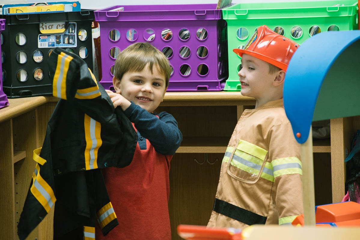 Two children in firefighter costumes in a classroom