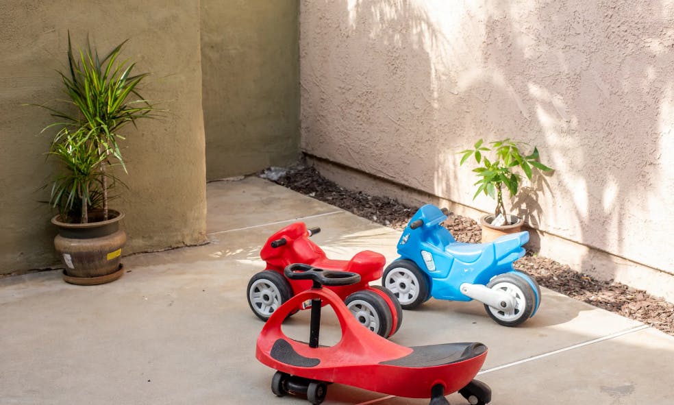 Red and blue toy motorcycles and a red ride-on toy