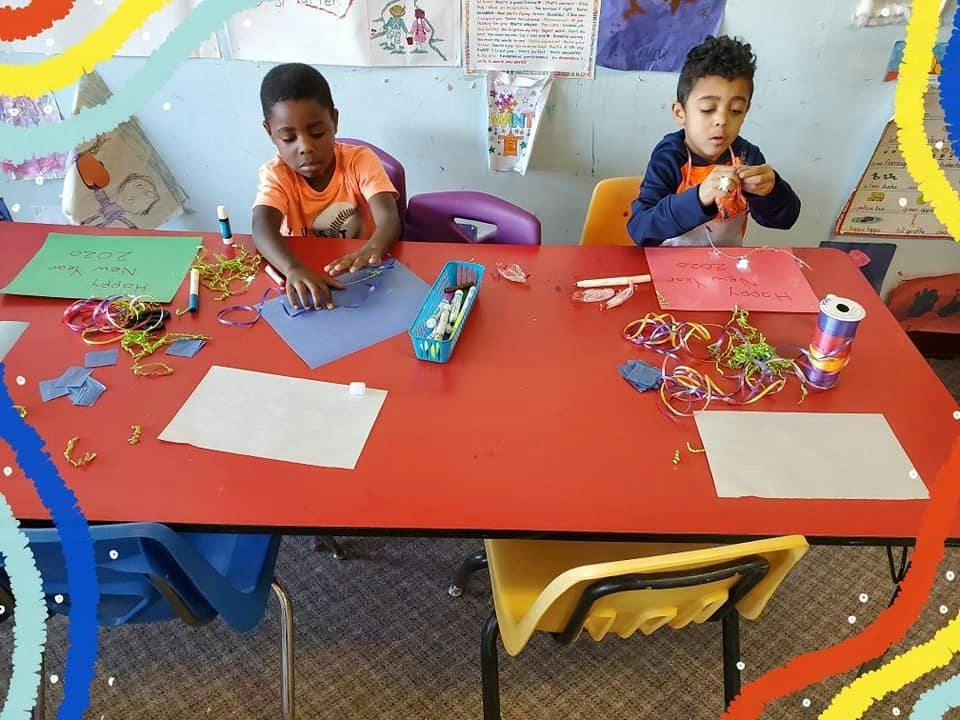 Two children doing crafts at a red table