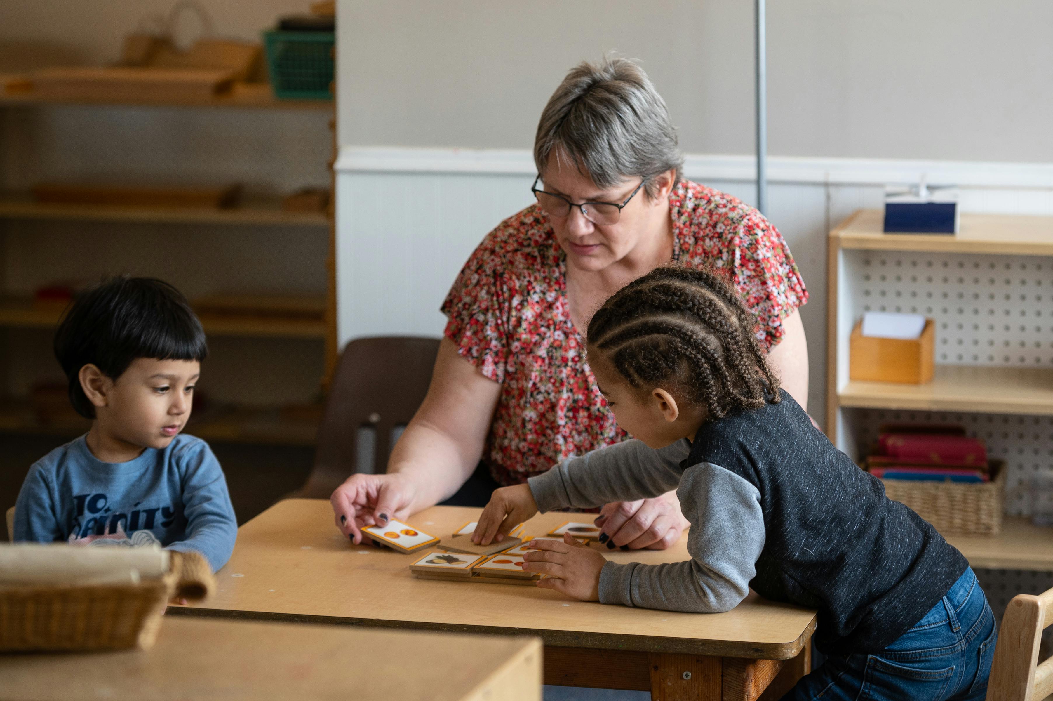 Adult and two children at a table playing a game with cards