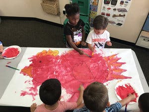 Children painting on a large sheet of paper