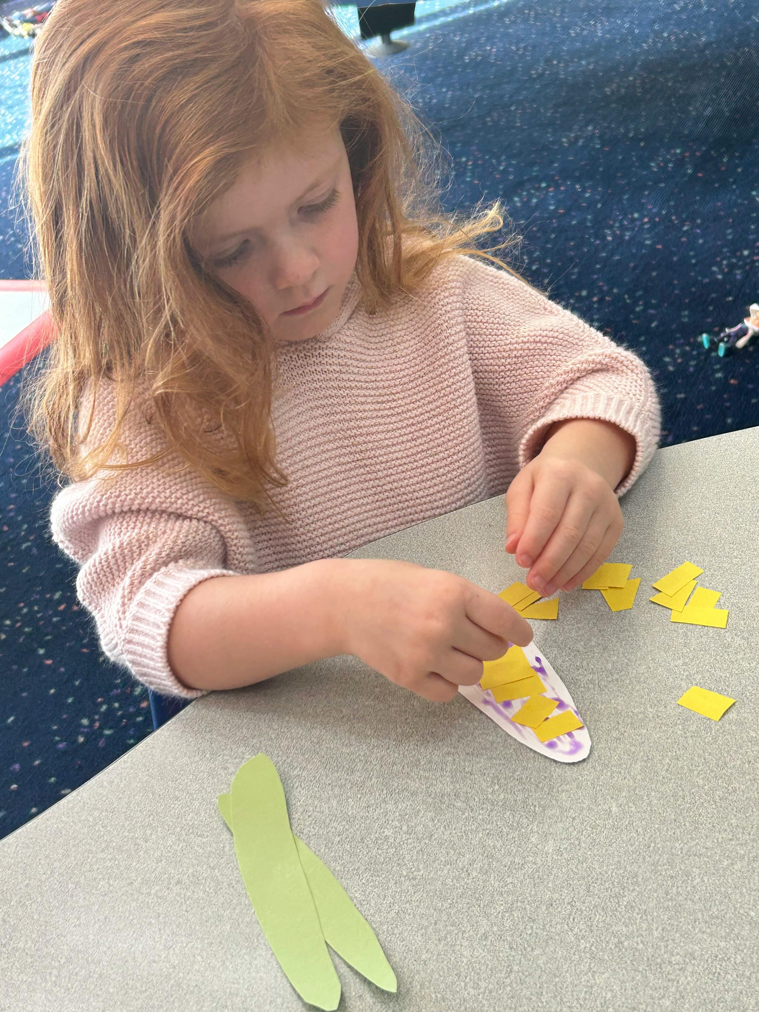 Child making a craft with paper cutouts