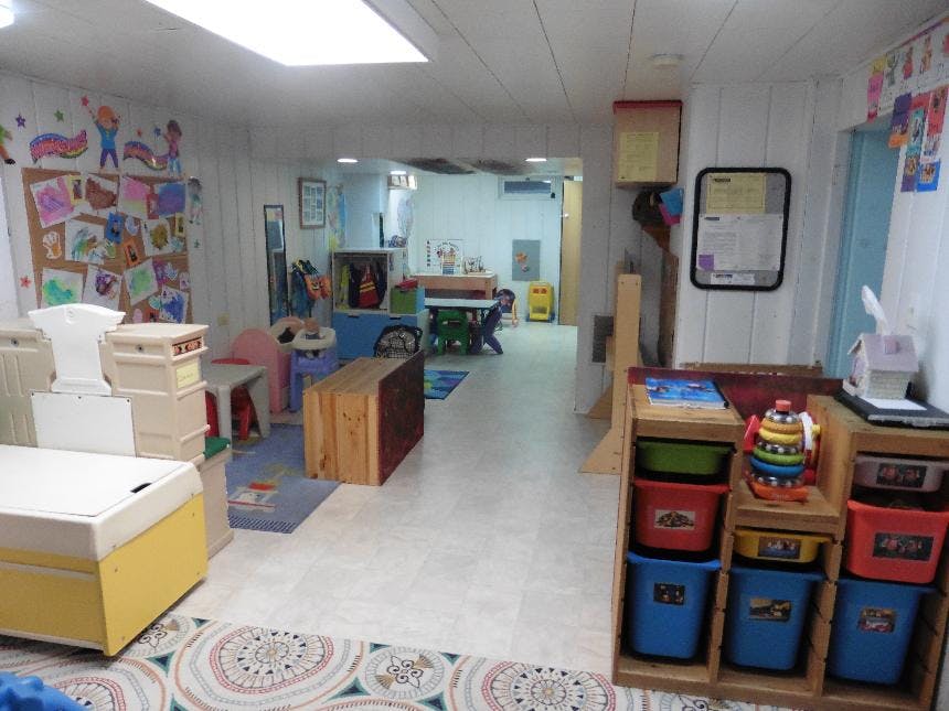 Playroom with colorful storage bins and children's artwork on the wall