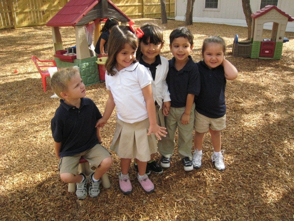 Five children standing on wood chips in a playground
