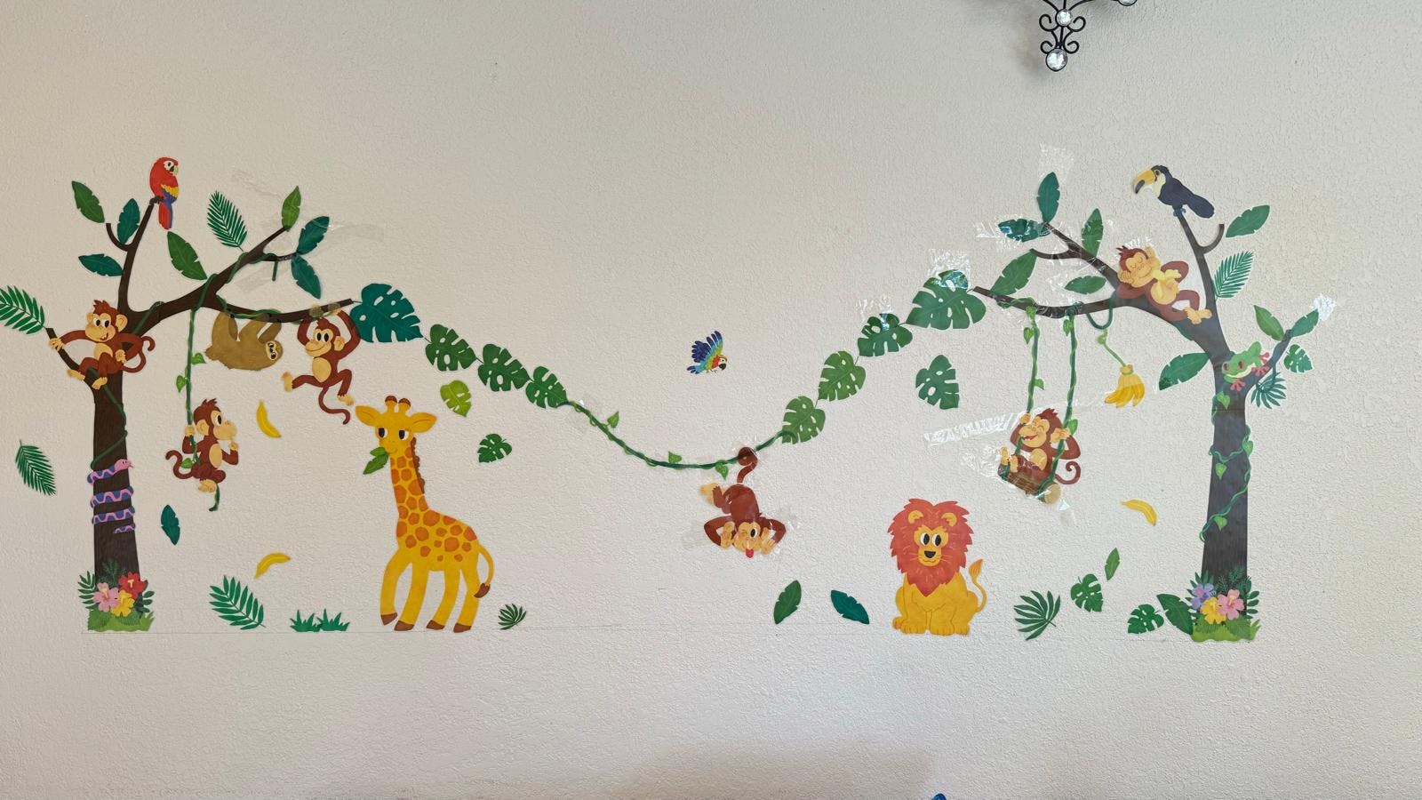 Wall decal of jungle animals including monkeys, giraffe, lion, and toucan