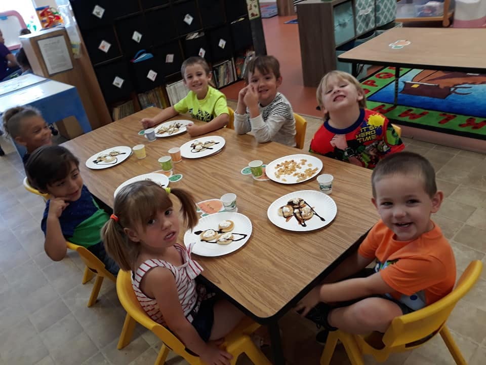 Children sitting at a table with plates of food