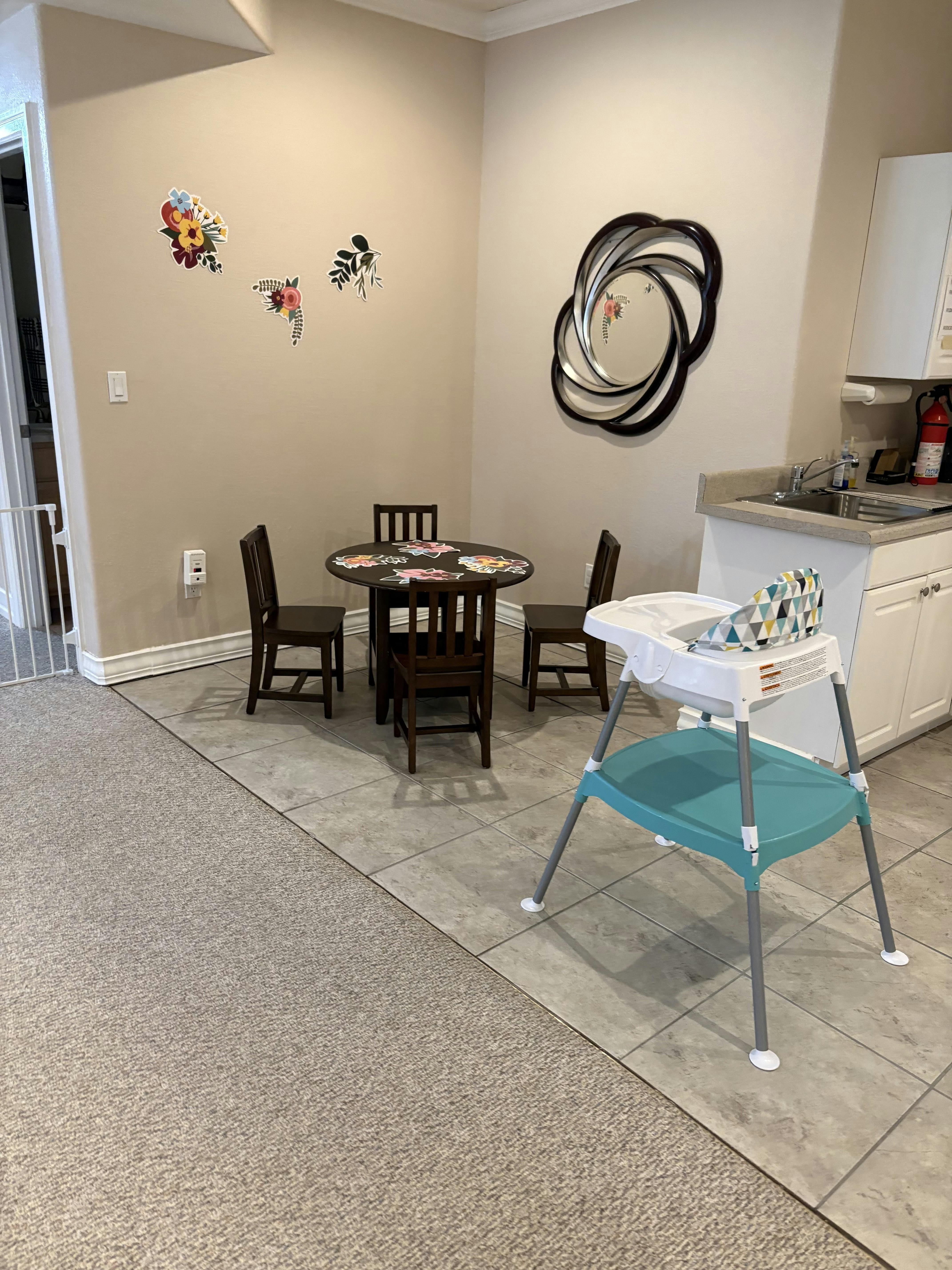 Small wooden table with four chairs and a baby high chair in a room