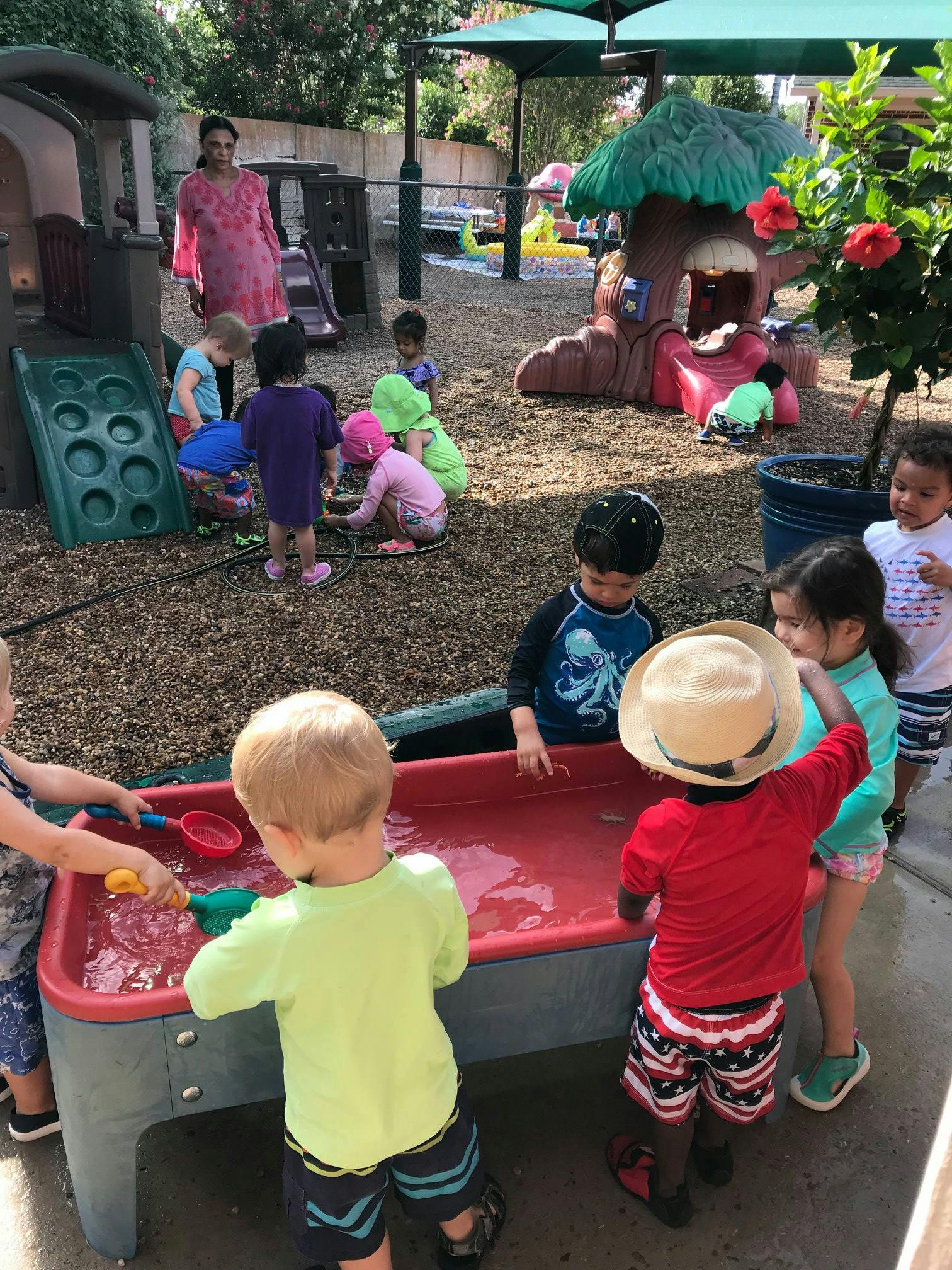 Children playing with water and toys in an outdoor play area