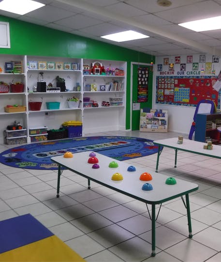 Classroom with shelves, tables, and a circular rug